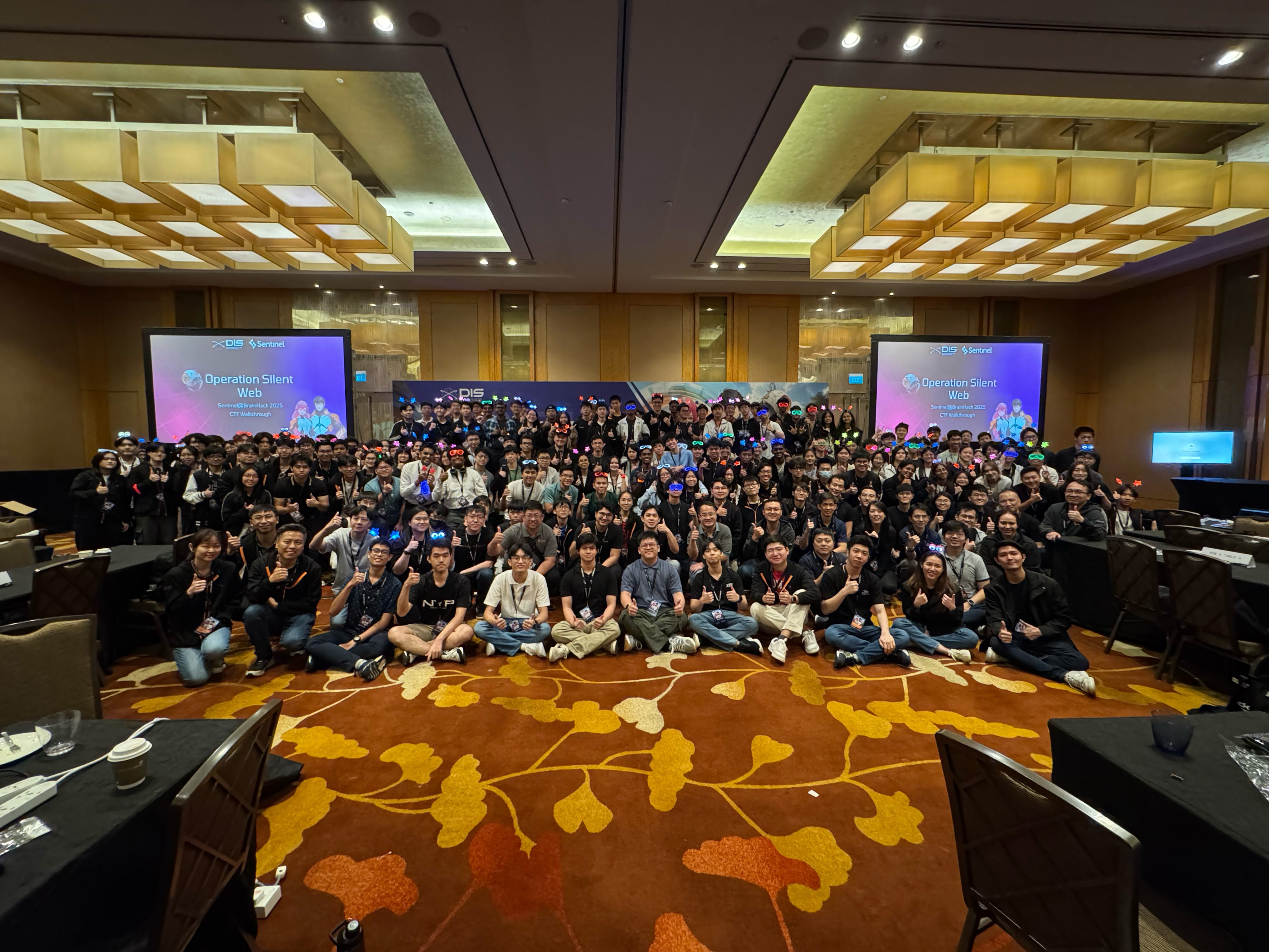 Group photo of participants at the Sentinel Challenge 2025 event with colored headgear and a presentation backdrop.